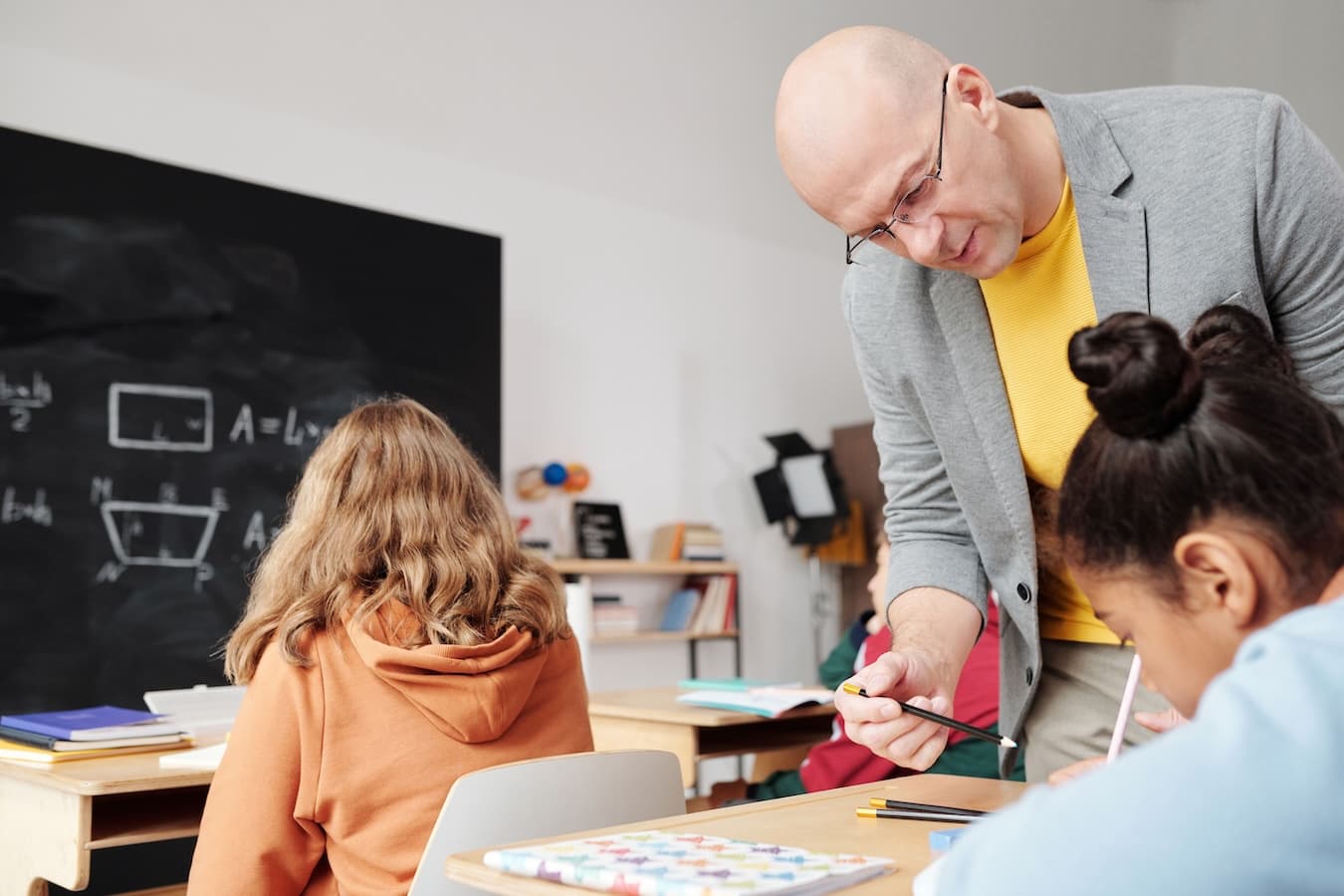 Enseignant accompagnant deux élèves pendant un exercice en classe
